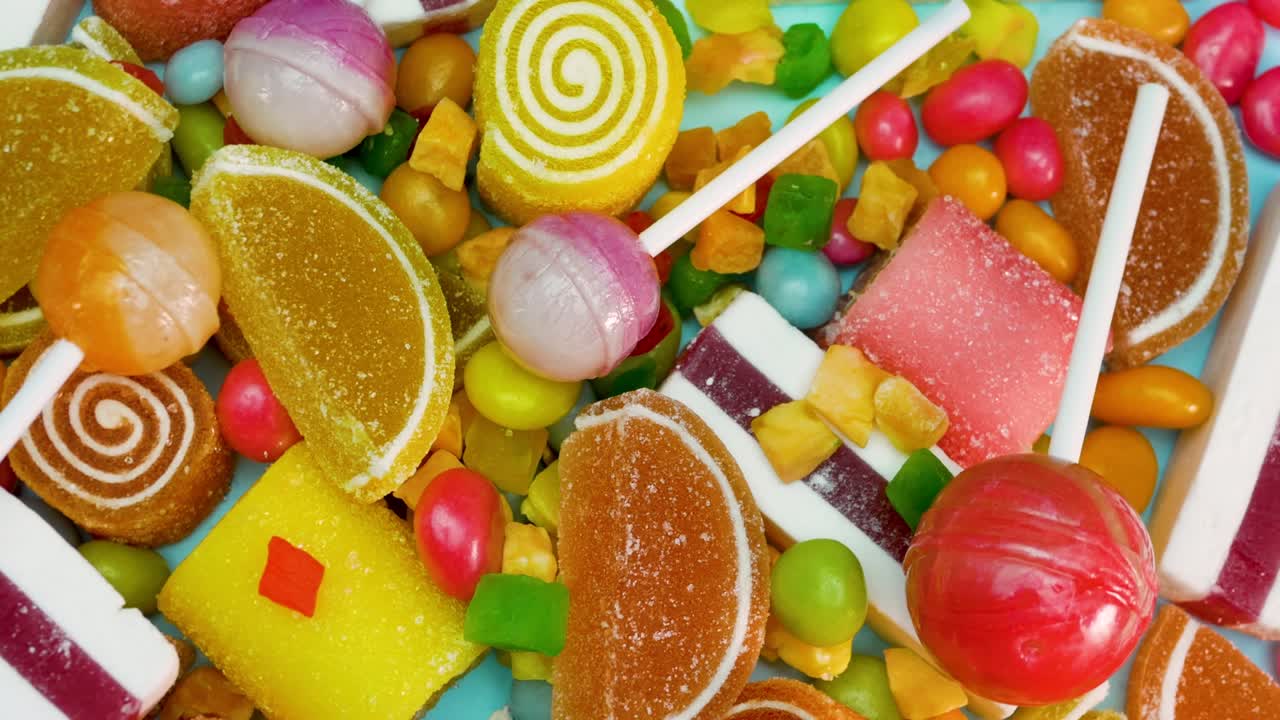 piruletas, mermelada de naranja y limón, malvaviscos de vainilla, dulces de colores mixtos están girando. dulces para niños