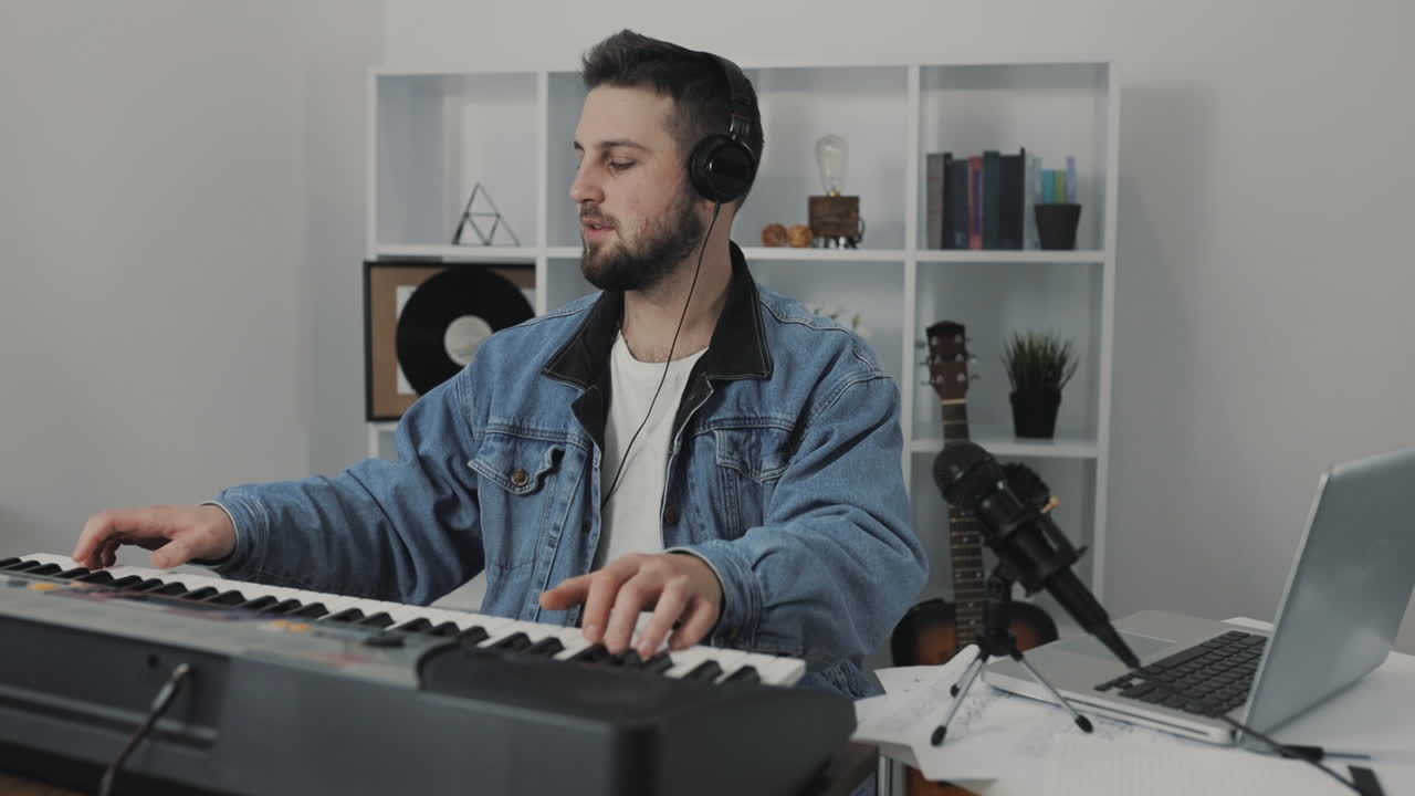 músico masculino tocando el teclado eléctrico mirando la cámara en casa