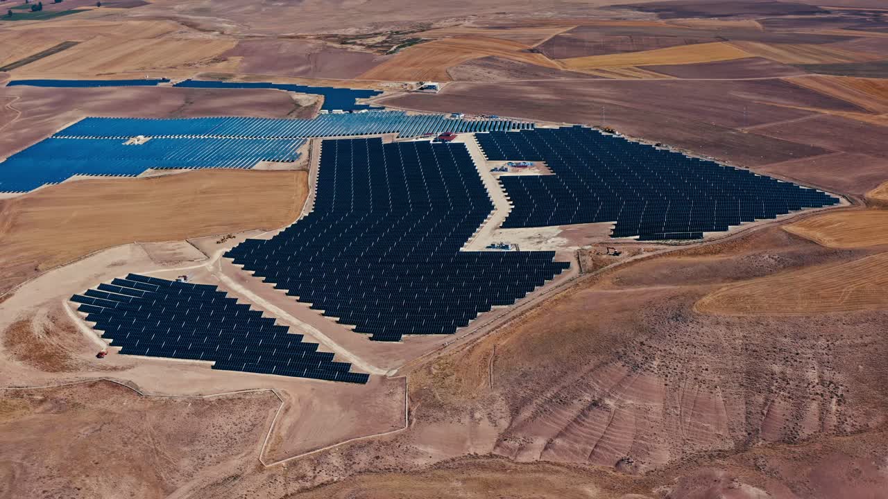 una impresionante vista aérea de una granja solar a gran escala en un paisaje seco, que muestra filas de paneles solares que generan energía limpia y renovable