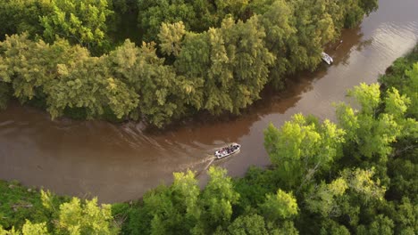 a stream in the amazon rainforest at sunset with a passing tourist boat