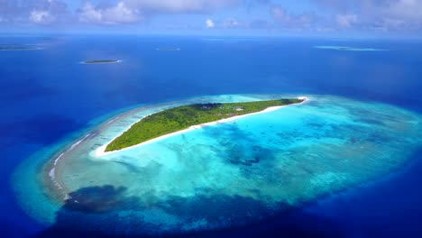 close-up,-bird's-eye-view,-high-altitude-aerial-view-of-a-small-island-covered-with-palm-trees-in-the-Caribbean-sea-as-the-color-of-the-sea-goes-from-turquoise-to-dark-blue