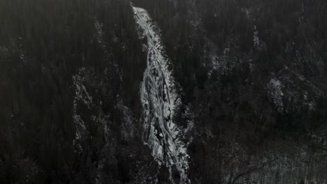stream with melting snow flowing through a mountain landscape in vallee bras-du-nord in quebec, canada - aerial drone shot