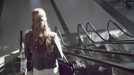 businesswoman moving downstairs on escalator in the office 4k