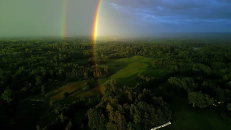 Double-rainbow-over-woodland-landscape,-aerial-drone-view
