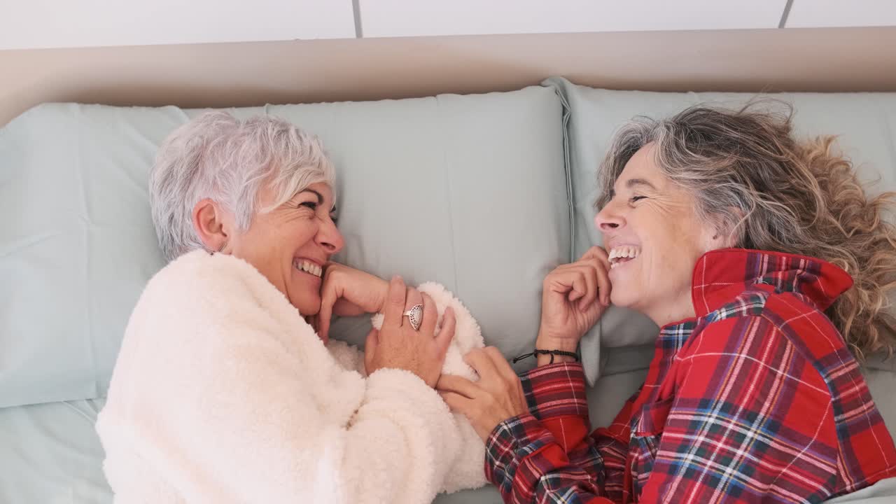 Two women laughing in bed
