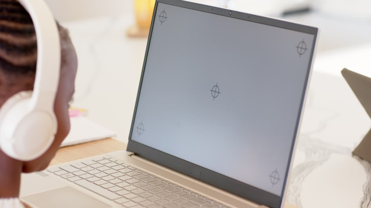 Schermo con mirino sul laptop che fa sì che il bambino si sporga in avanti, aggiustando la postura, seduto al tavolo