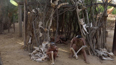 indigenous people statues crafting tools in a traditional village setting, daylight