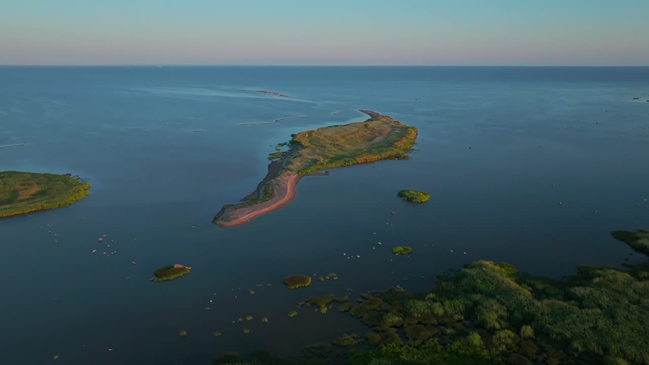 Drone shot of green island islet in summer, moving left to right revealing green coastline