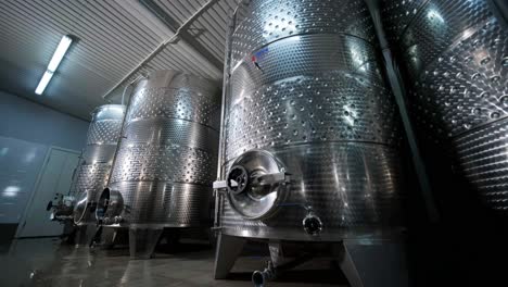 un agricultor o viticultor feliz está caminando en medio de tanques de vino y comprobando un grado de fermentación de la producción de vino de alta calidad en una instalación moderna de elaboración de vino o bodega.