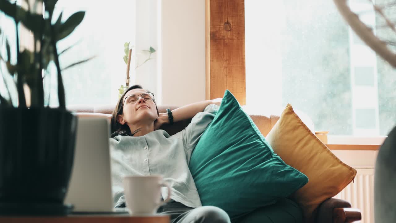 Woman taking a break from her laptop work by relaxing on the sofa