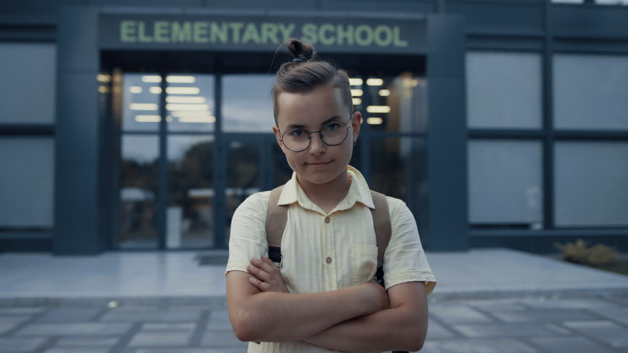 Elementary age guy posing on schoolyard alone close up. Pupil standing at campus