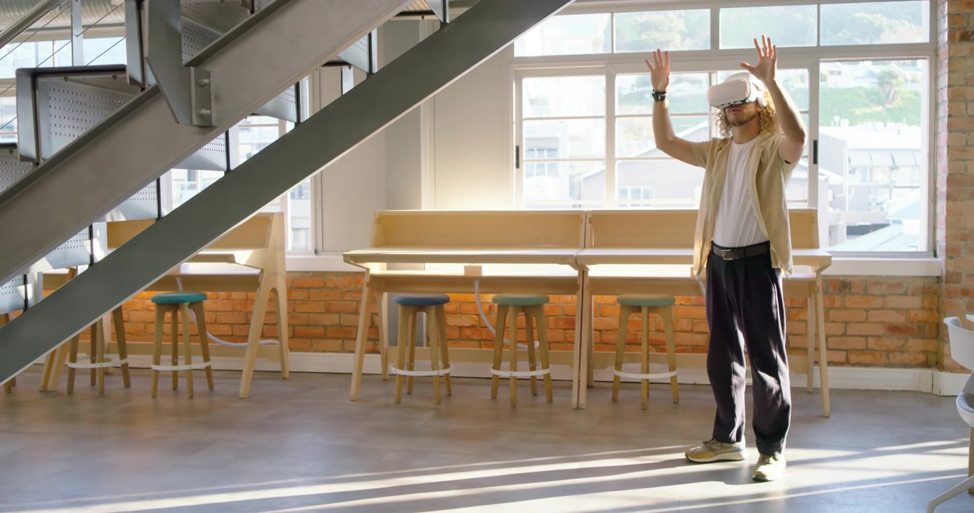 Após o headset ligar, homem adulto em pé em um loft gesticulando e explorando uma demonstração de RV, com espaço para texto.