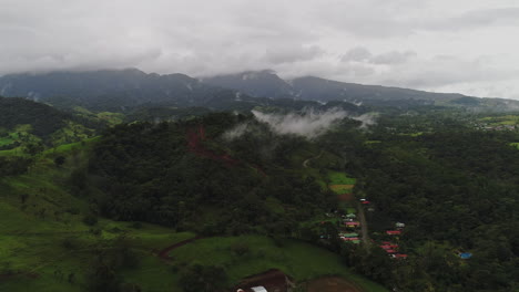 aerial over rural central american houses with cloudy mountains in background, 4k