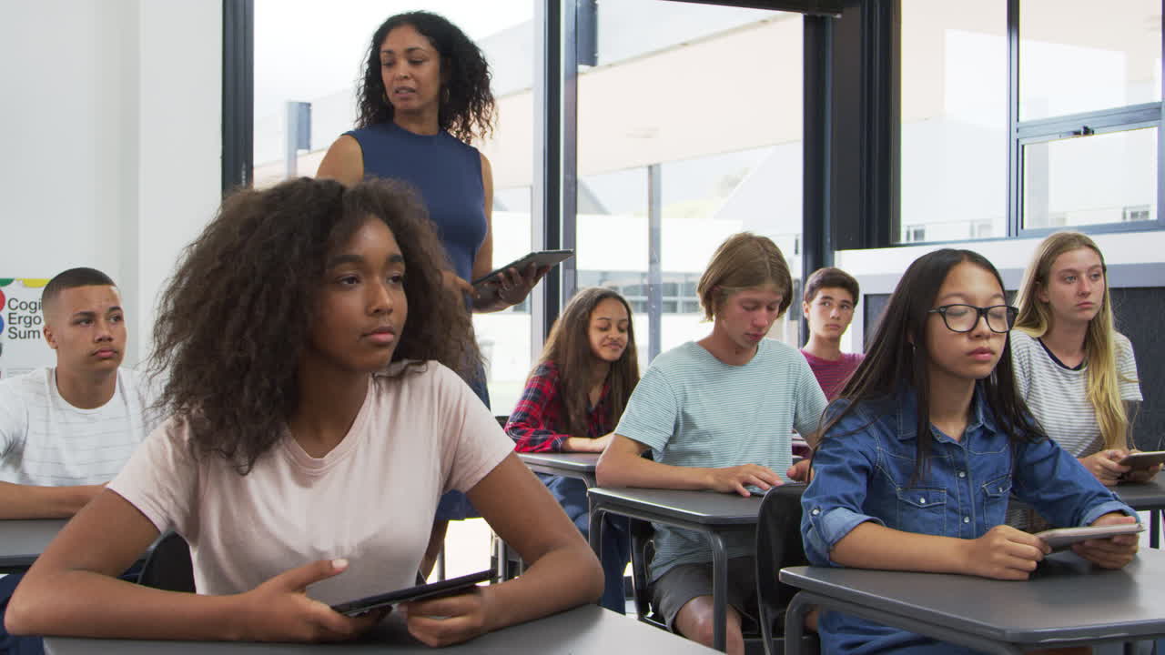 Teacher addressing pupils from the back of her high school class
