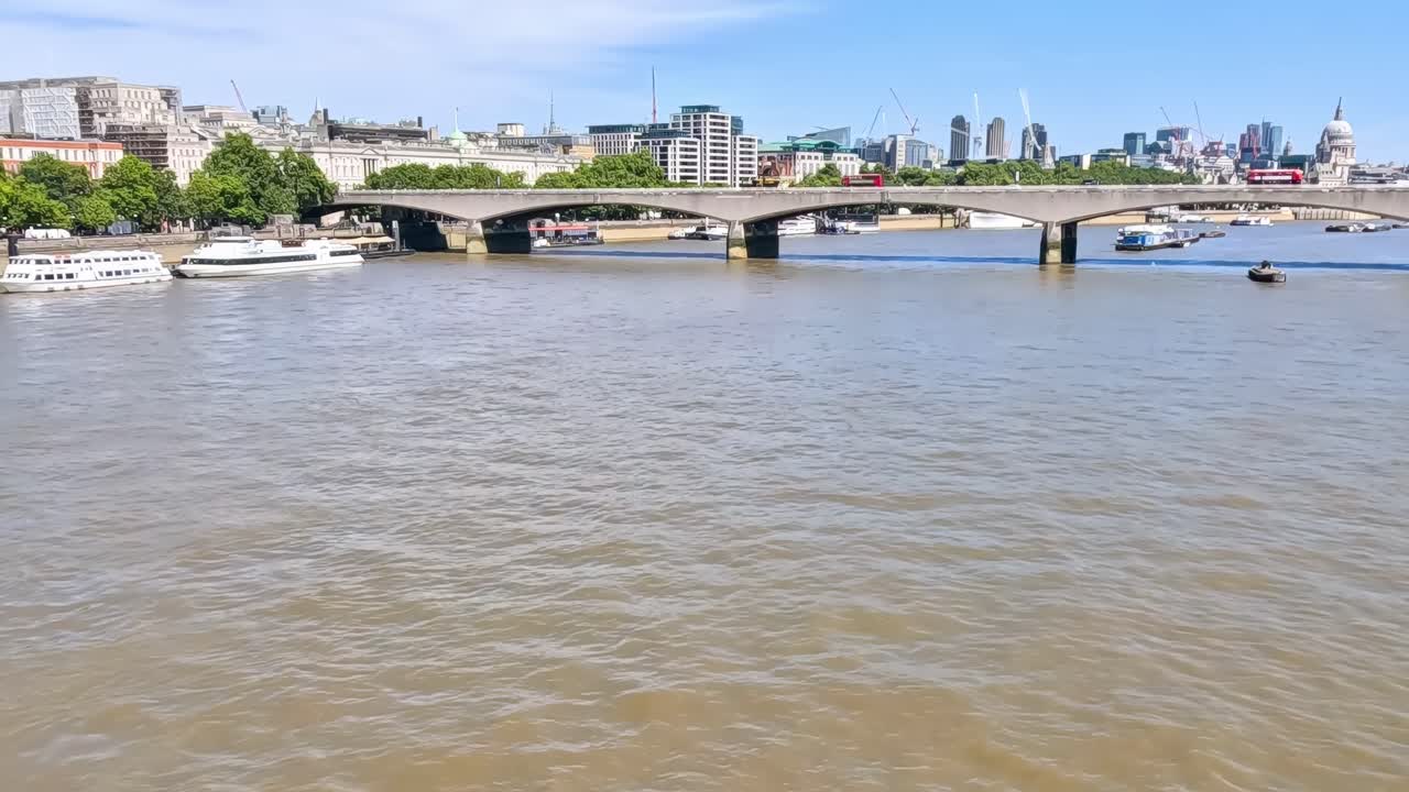 A scenic view of a bridge over a river with boats passing by on a clear, sunny day.