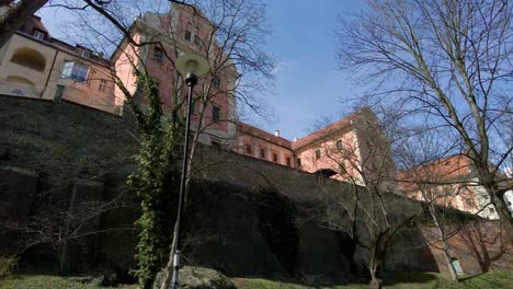 Historic-buildings-of-the-city-of-Olomouc-standing-on-the-high-stone-walls-on-a-spring-day,-view-from-the-park