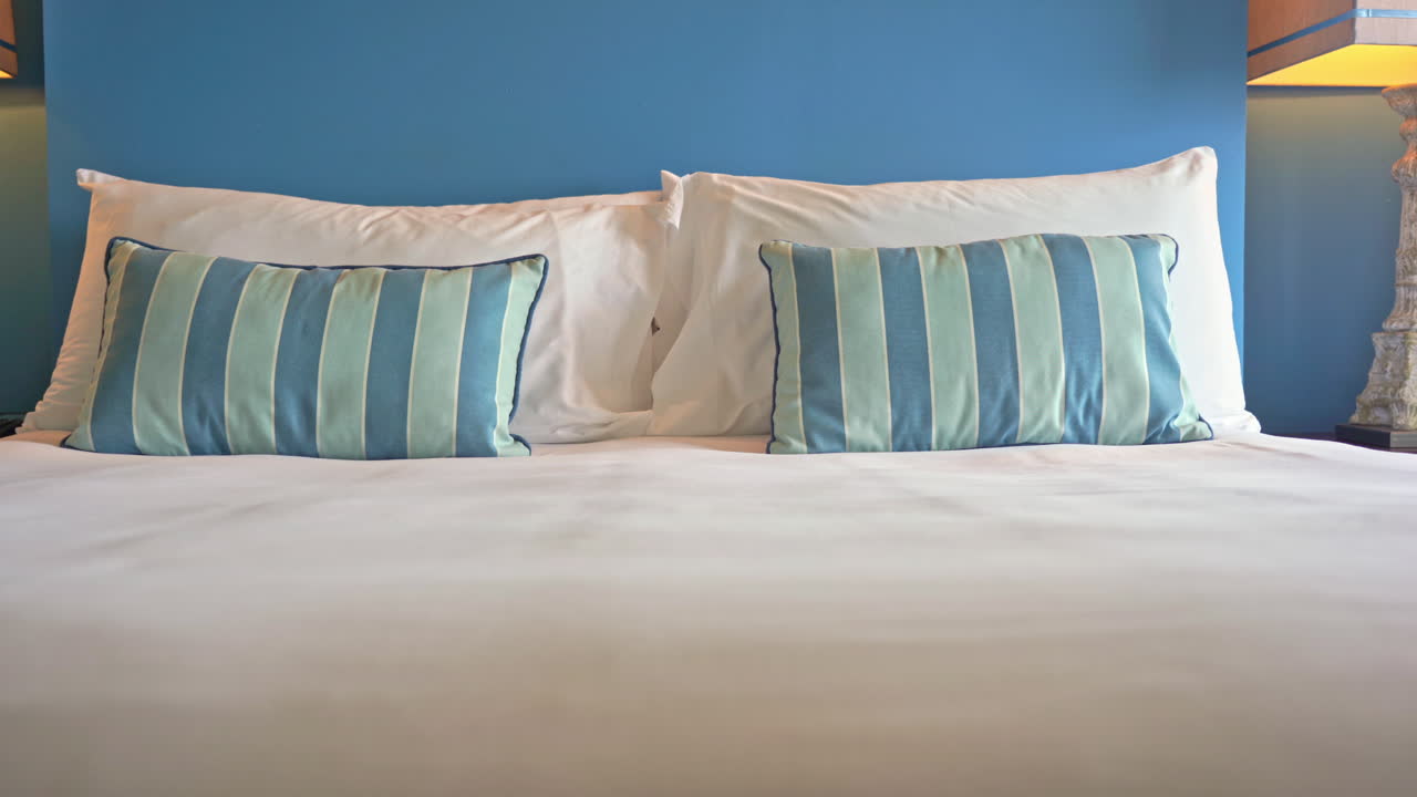 줄무늬 장식 베개로 장식된 호텔 리조트 침대를 가로질러 이동