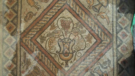 ancient roman mosaic on the floor of an old building atop a hill, surrounded by the emerald waters of lake lin, pogradec