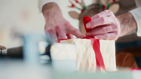 little boy watches his dad wrapping christmas presents