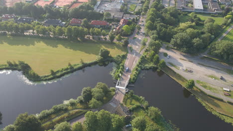 Aerial-orbit-of-car-driving-over-small-bridge-over-river-in-the-Netherlands