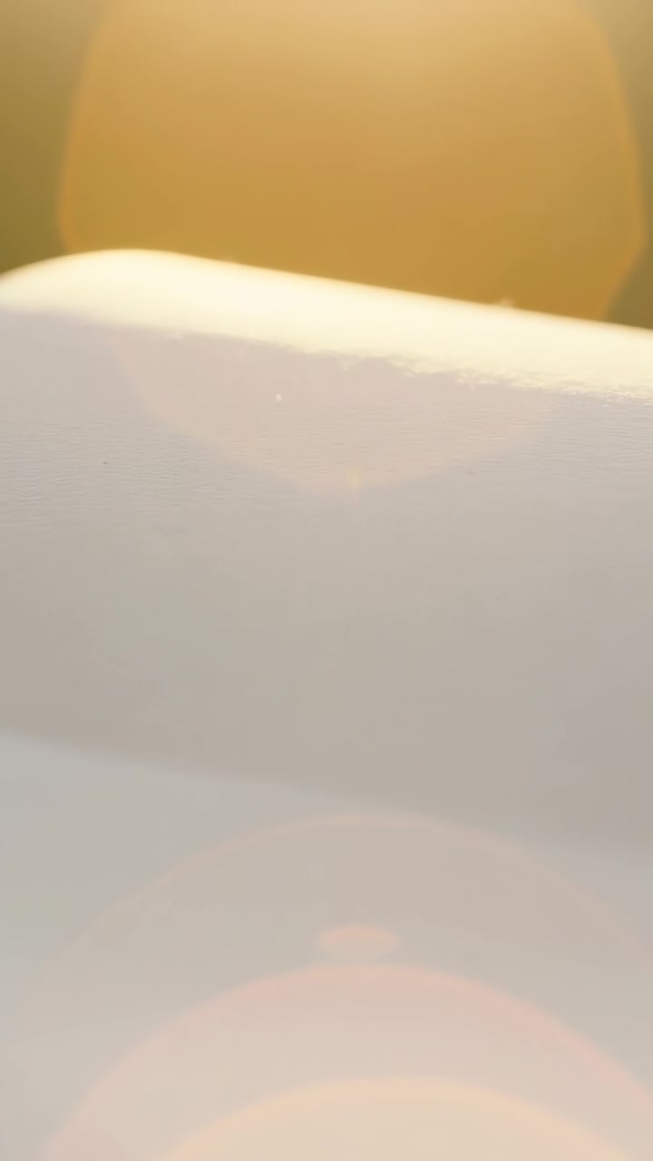 Video verticale: Telecamera del telefono che effettua una panoramica, mostrando un primo piano di un letto in tessuto morbido, rivelando un alone e un bagliore dell'obiettivo.