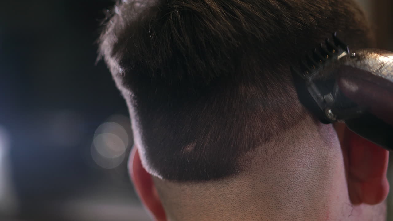 Close-up view on male's hairstyling in a barber shop with professional trimmer. Man's haircutting at hair salon with electric clipper. Grooming the hair.