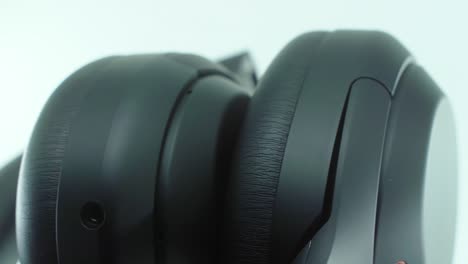 una toma cinematográfica de acercamiento, video de producto 4k, juego de auriculares inalámbricos negros, auriculares suaves, luz de estudio, cámara lenta, soporte giratorio