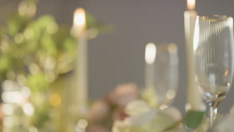 Close-Up-Of-Candles-Flowers-And-Glasses-On-Table-Set-For-Meal-At-Wedding-Reception-In-Restaurant