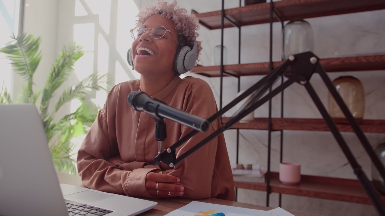 Ung afrikansk kvindelig blogger optager online podcast ved hjælp af streamingmikrofon