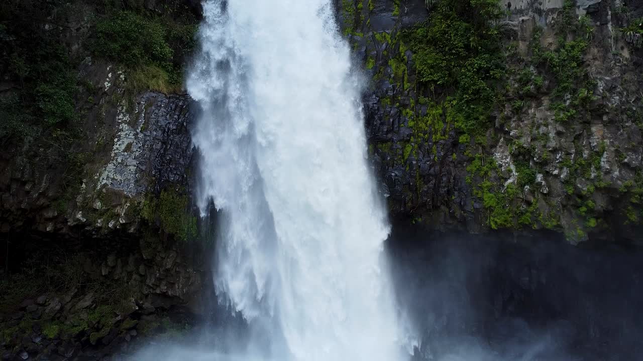 dramática cascada de agua desde un barranco rocoso escarpado en una piscina de niebla