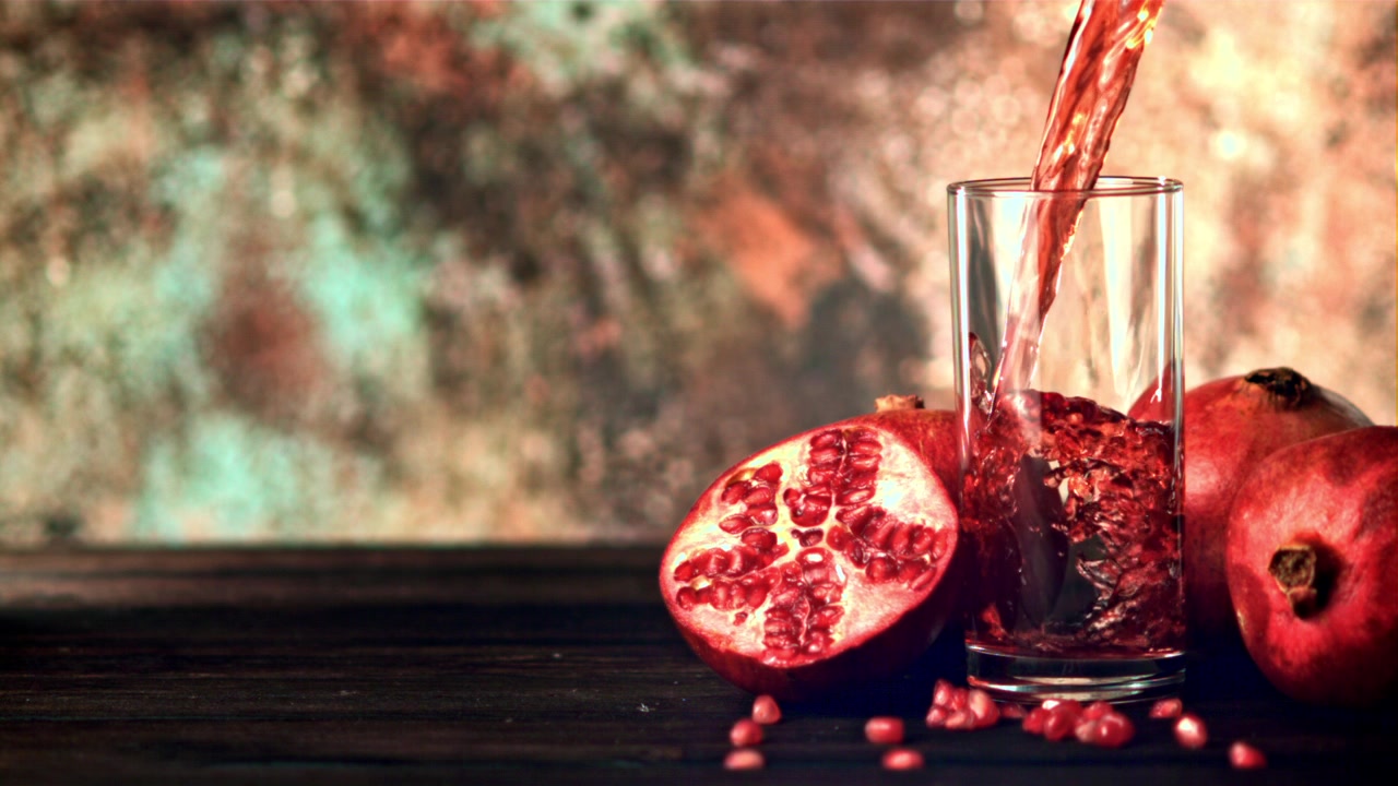 Frisk granatæblejuice hældes i et glas i slow motion