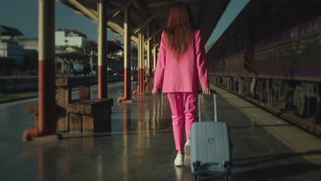 woman in pink suit at train station