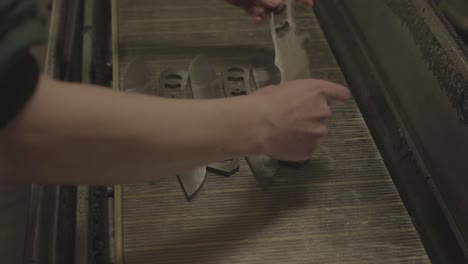 lining up stainless steel patterns of military knives, preparing for sanding and polishing in industrial process, close up