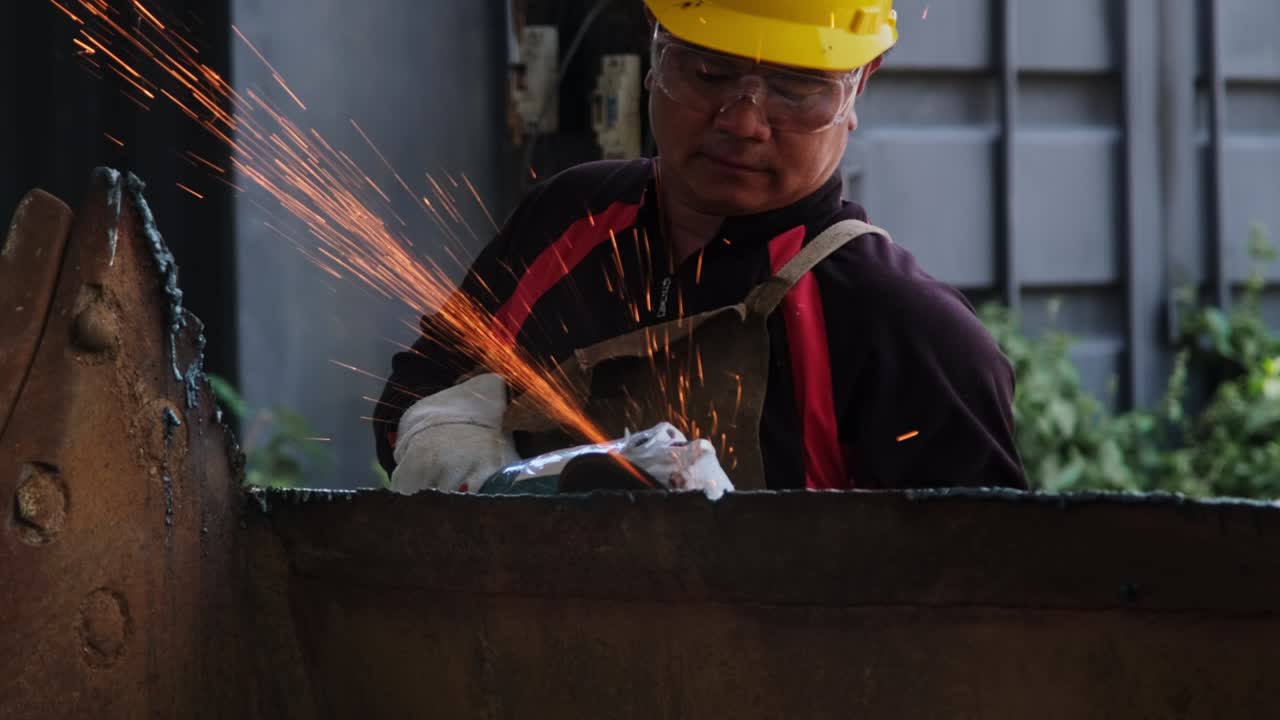 Man work in home workshop with angle grinder, goggles and construction gloves. Sanding metal makes sparks, closeup