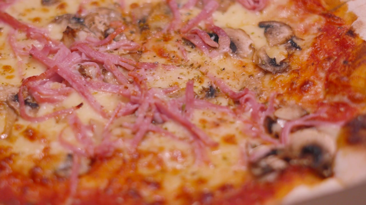 Vista dall'alto di una pizza prosciutto e funghi con gustosa mozzarella su crosta sottile.