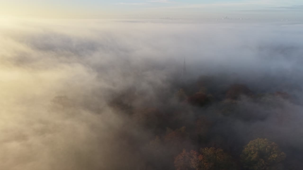 Church steeple rises through misty morning fog Epping Forest UK drone,aerial