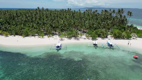 banca outrigger boats of balabac palawan islands on clear ocean water, palm trees