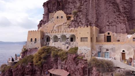 Santorini-Greece,-Castle-Resort-Building-on-a-Cliff-Face,-White-Buildings-Overlooking-Mediterranean-Sea