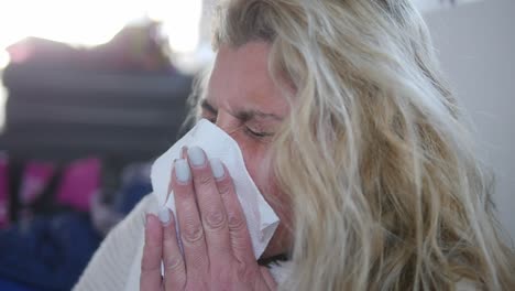 close-up of a sick woman sneezing multiple times into a tissue