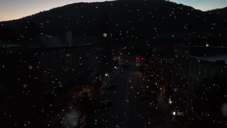 snowflakes fall at mountain ski resort town at night