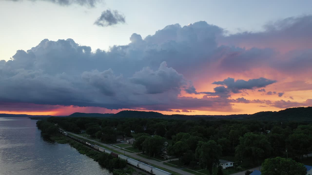 Aerial View of Dramatic Sunset Over River, Train, and Rural Town