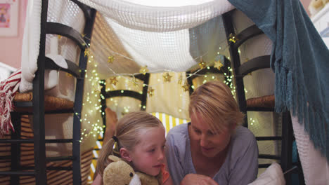 front view of caucasian woman reading a story to her daughter at home