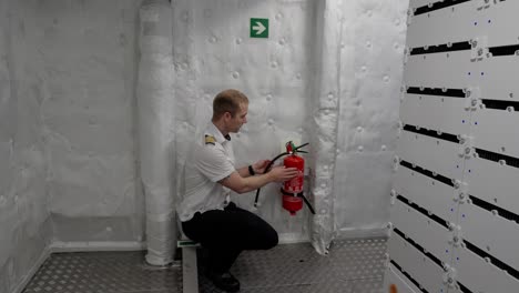 el capitán del barco está mostrando el extintor de incendios en la sala de motores y baterías del barco.