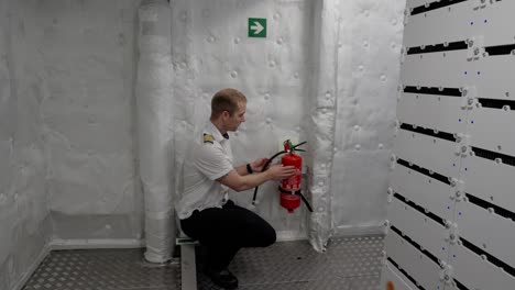 ships captain is showing fire extinguisher in ships engine and battery room