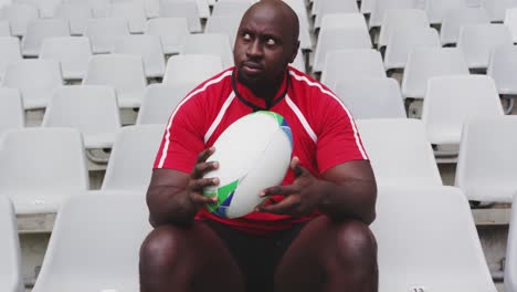 male rugby player sitting with rugby ball in stadium 4k