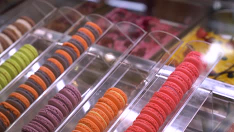 filas de macarrones coloridos en exhibición en una pequeña tienda de postres