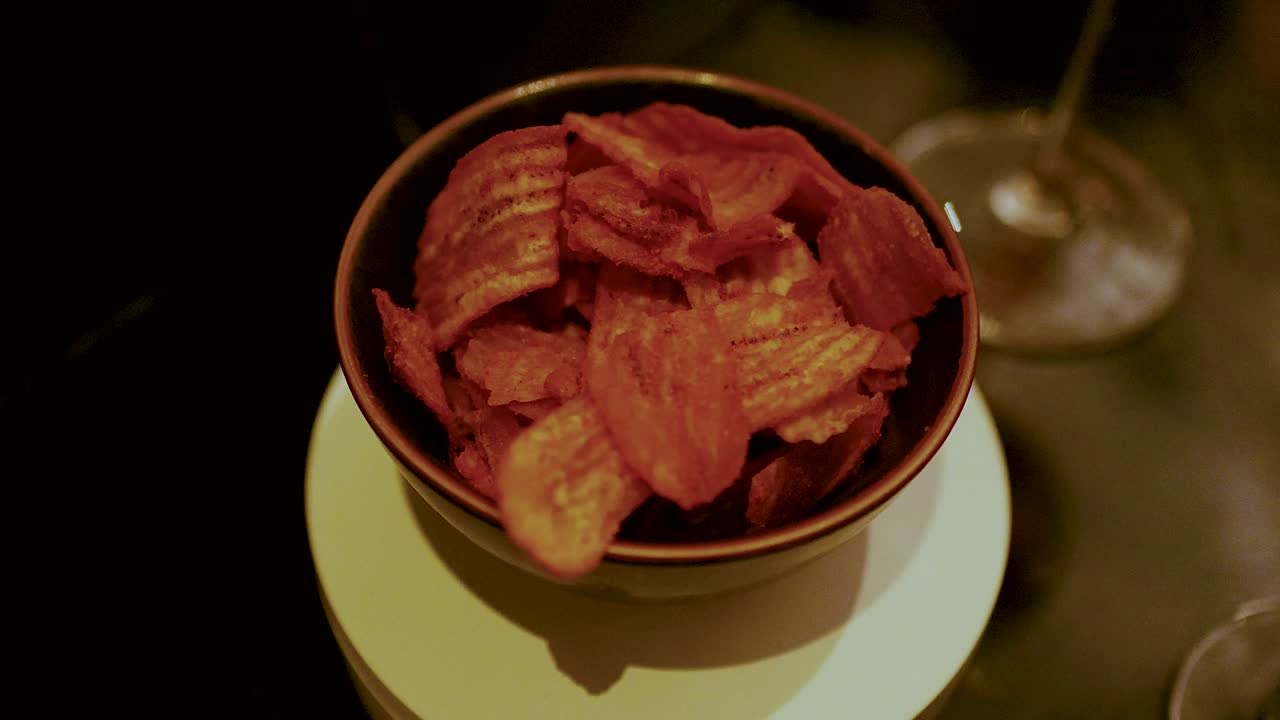 Bowl of chips with cocktail glass nearby