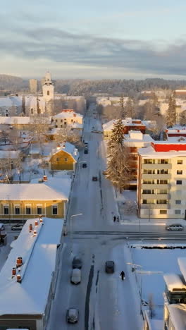 Vertical drone shot over snowy streets of Kuopio city, winter sunrise in Finland