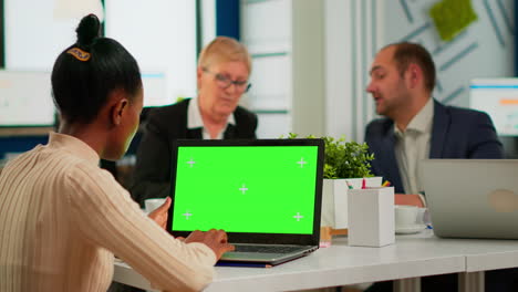 african manager woman sitting at conference desk looking at laptop with green screen