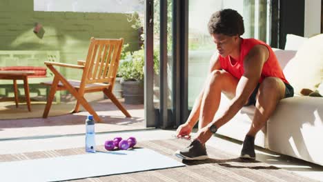 Fit-african-american-man-exercising-at-home-and-tying-the-laces